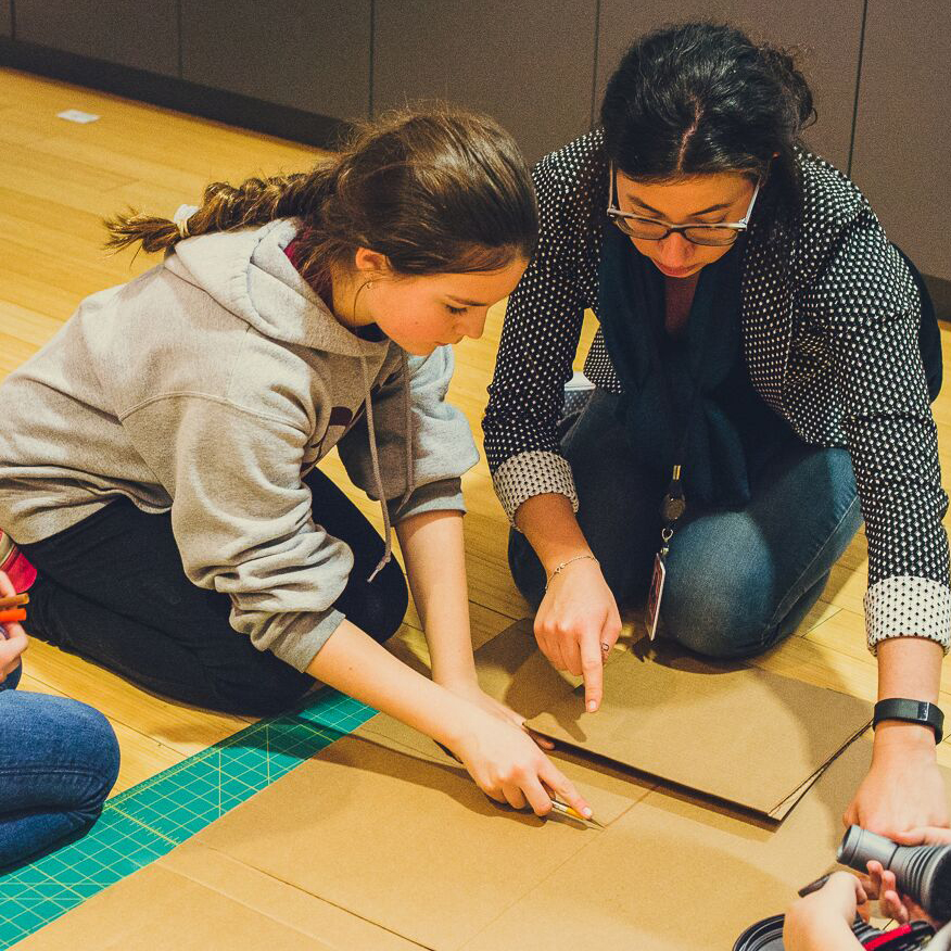 A Dyson engineer helping a student build her cardboard prototype.