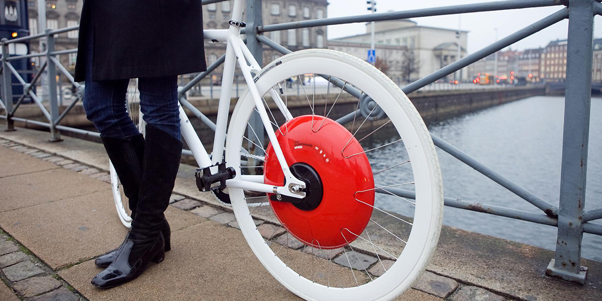 Person standing next to a bike with a Copenhagen Wheel.