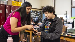Two students using one of the air quality monitoring devices in a classroom.