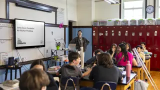 A group of students in a classroom with a representative of the James Dyson Foundation who's hosting a prototyping workshop with them.