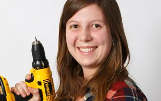 A female Dyson engineer holding a yellow drill.