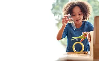 A young child cutting sellotape.