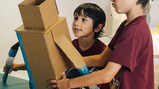Two students building a prototype from cardboard and excess Dyson machine parts.