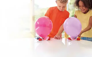 Two students building a balloon car.