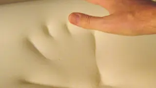 A close-up of a hand on a memory foam mattress.